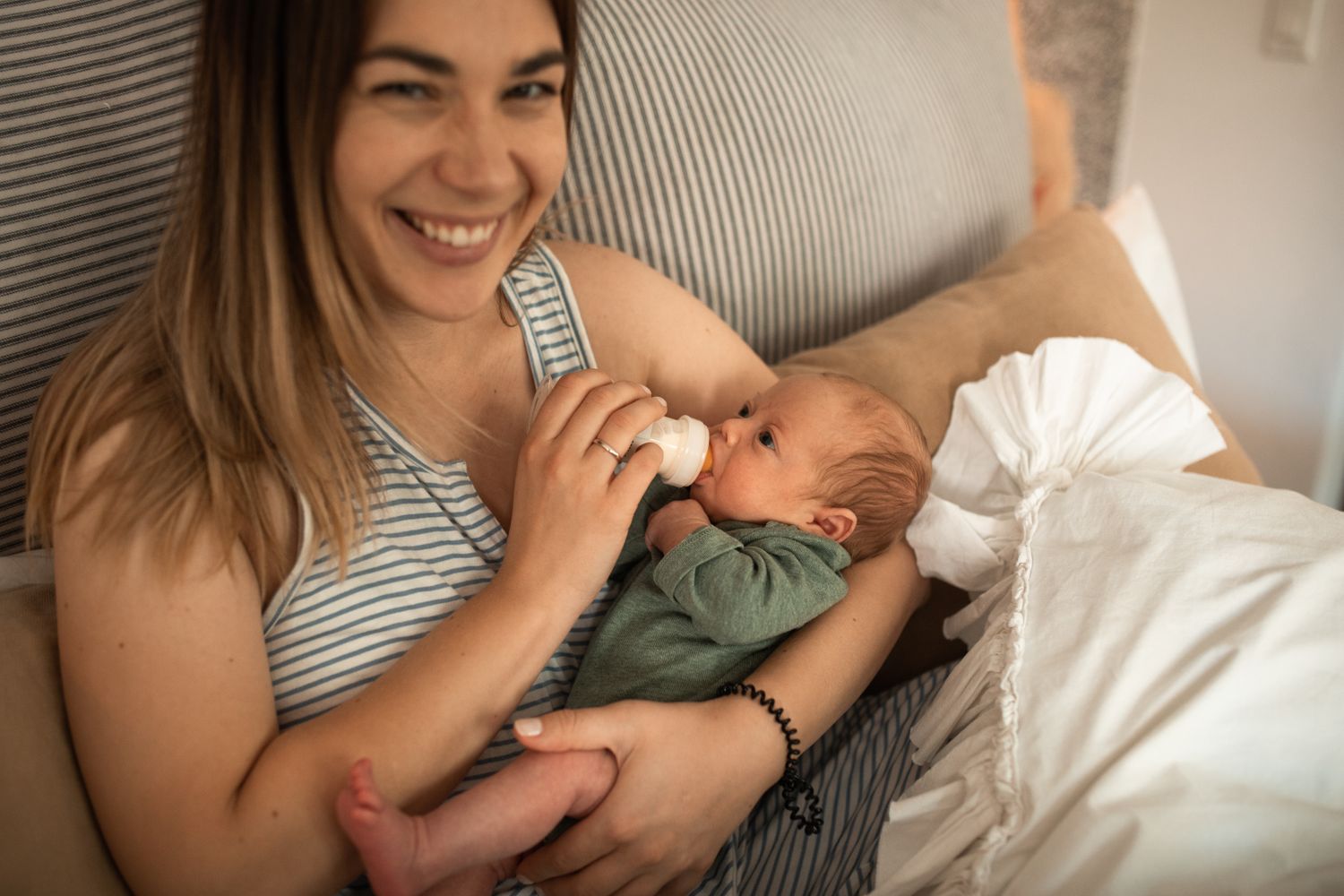 Lachende moeder geeft haar pasgeboren baby de fles